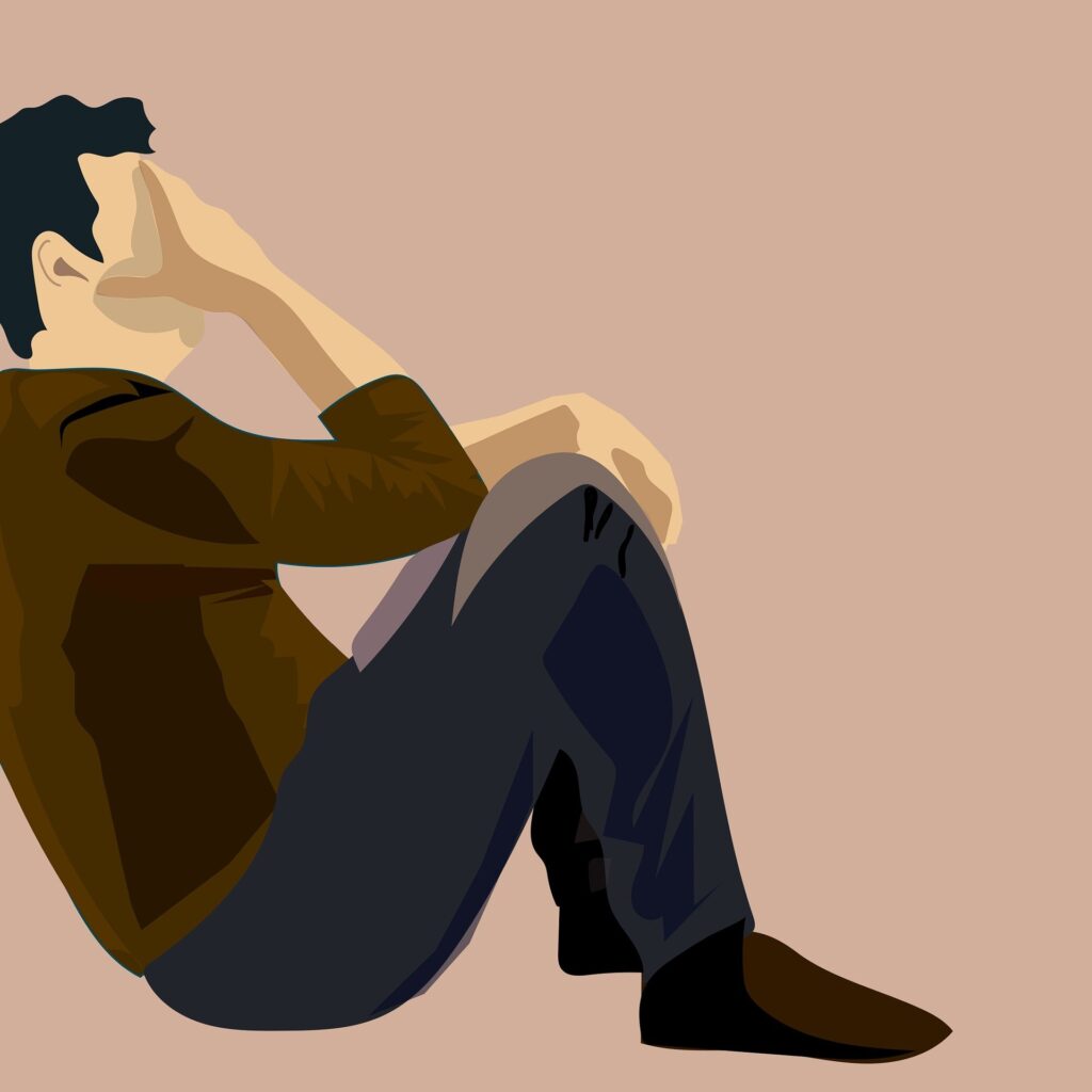 man covering face against wall